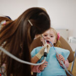 Young child receiving dental examination with suction tool during tooth injury evaluation.