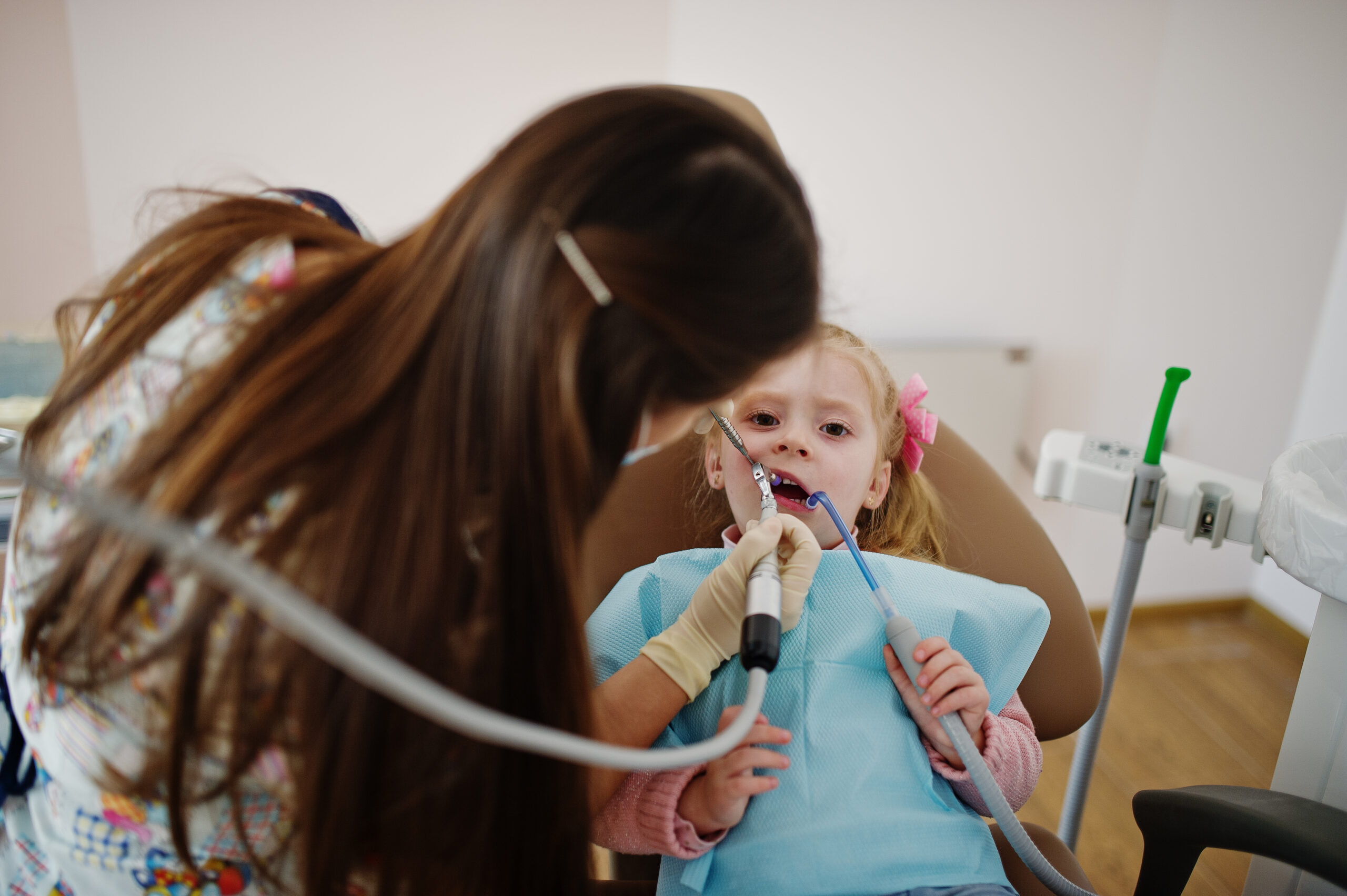 Young child receiving dental examination with suction tool during tooth injury evaluation.