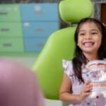 Happy child holding dental model with braces in orthodontist chair at Spring dental office.
