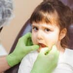 Young patient receiving dental examination in chair at Spring pediatric practice.