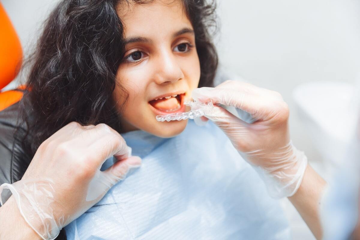 Child receiving clear aligner tray placement during dental visit in Spring, TX.