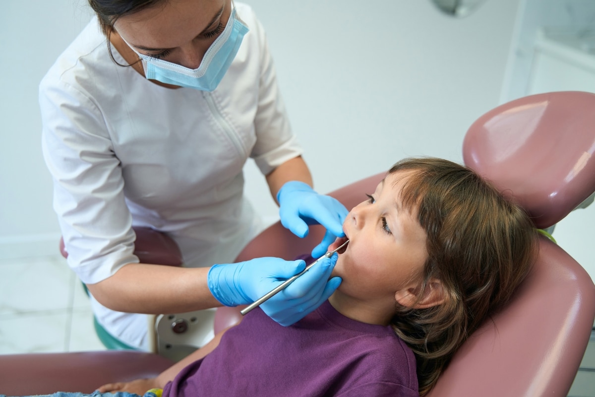 Pediatric dentist examining a child during baby tooth root canal treatment