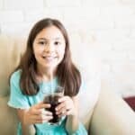 Child drinking a sugary soda while learning about cavity prevention