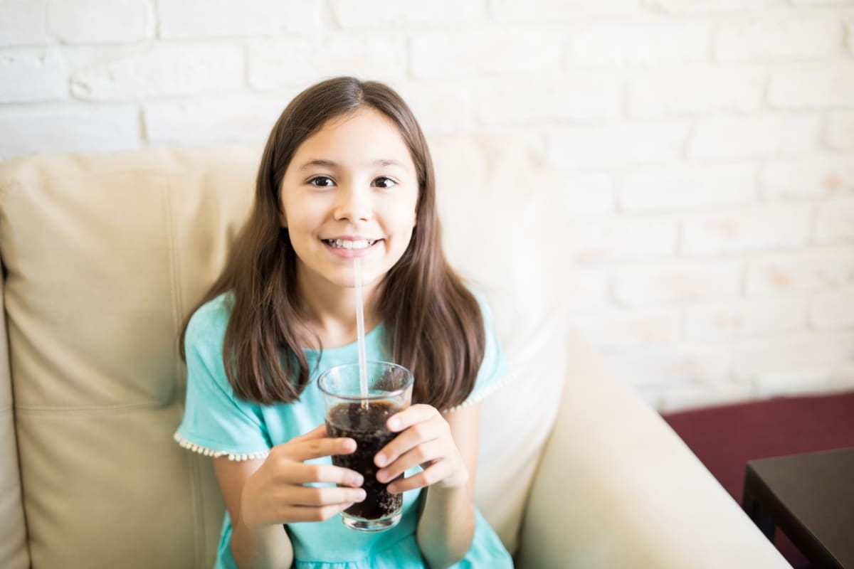 Child drinking a sugary soda while learning about cavity prevention